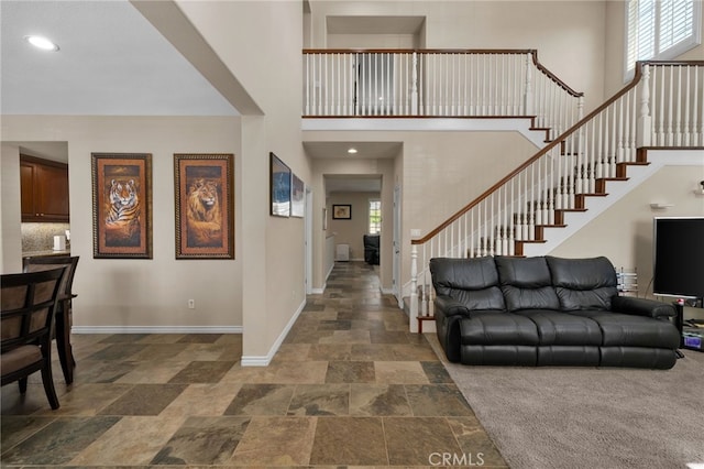 14538 Eagle River Rd, Eastvale, CA 92880 - entrance foyer with stone tile floors, a towering ceiling, stairway, baseboards, and recessed lighting