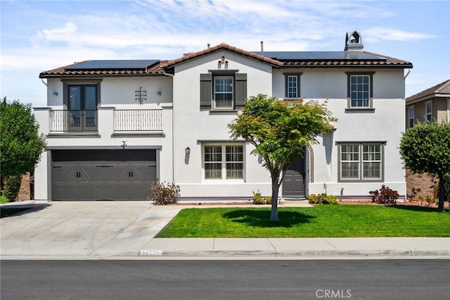 14538 Eagle River Rd, Eastvale, CA 92880 - mediterranean / spanish home featuring a balcony, roof mounted solar panels, a front lawn, and an attached garage
