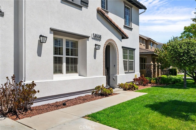 14538 Eagle River Rd, Eastvale, CA 92880 - doorway to property featuring a yard and stucco siding