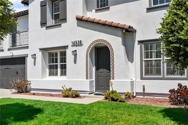 14538 Eagle River Rd, Eastvale, CA 92880 - doorway to property featuring a garage, stucco siding, a lawn, and a tile roof