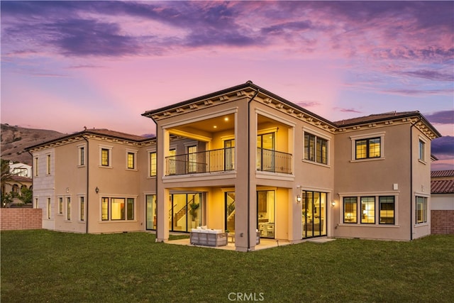 100 Headwaters, Irvine, CA 92602 - back of property at dusk with a balcony, a lawn, stucco siding, outdoor lounge area, and a patio area
