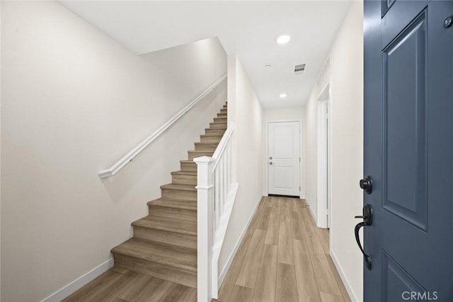 staircase featuring baseboards, wood finished floors, and recessed lighting