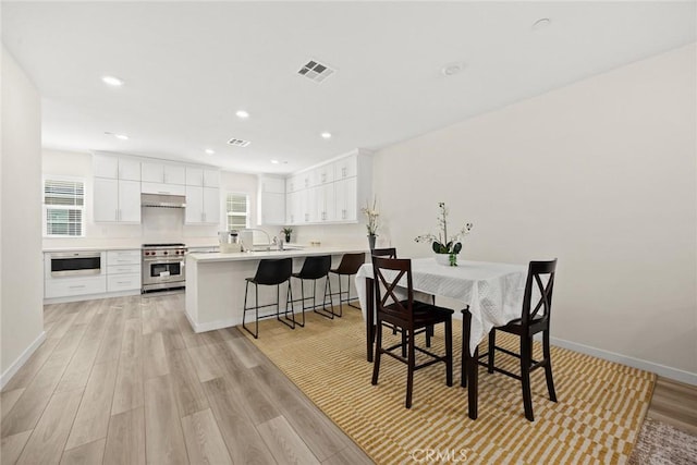 dining space with light wood finished floors, baseboards, and recessed lighting
