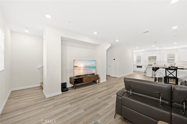 living area featuring light wood-style floors, baseboards, and recessed lighting