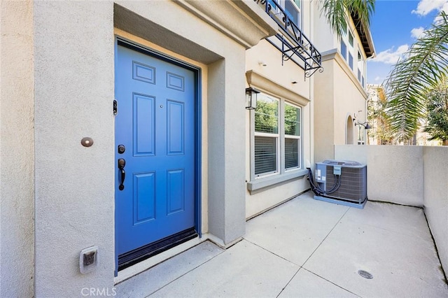 entrance to property with central air condition unit and stucco siding