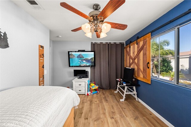 7189 Myrtle Pl, Fontana, CA 92336 - bedroom with a barn door, light wood-style floors, ceiling fan, and baseboards