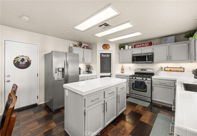 7189 Myrtle Pl, Fontana, CA 92336 - kitchen featuring appliances with stainless steel finishes, a kitchen island, light countertops, and dark wood-type flooring
