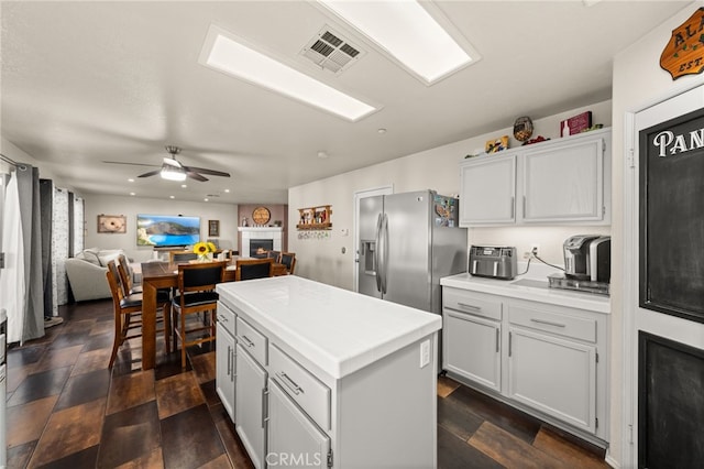 7189 Myrtle Pl, Fontana, CA 92336 - kitchen with stainless steel refrigerator with ice dispenser, a center island, a lit fireplace, open floor plan, and ceiling fan