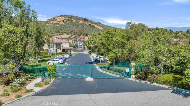 587 Fenwick Way Unit B, Simi Valley, CA 93065 - view of asphalt road featuring a gate, curbs, a mountain view, and a gated entry