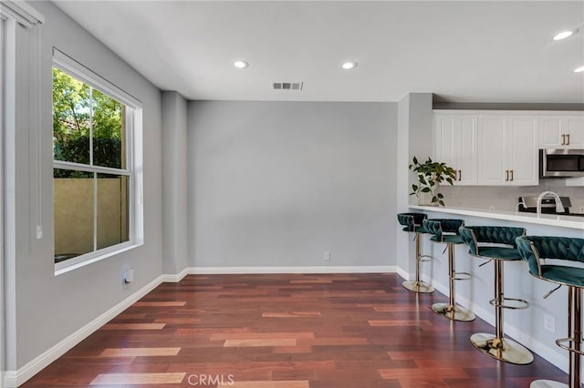 587 Fenwick Way Unit B, Simi Valley, CA 93065 - kitchen with stainless steel microwave, a breakfast bar area, dark wood-style floors, light countertops, and recessed lighting