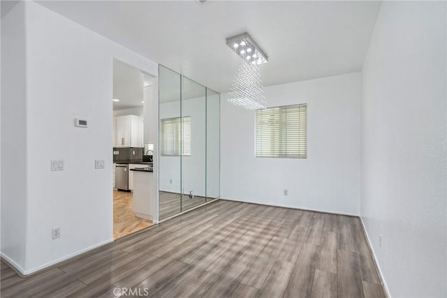unfurnished room with light wood-type flooring, baseboards, and a sink
