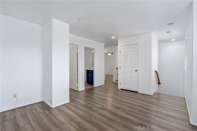 spare room with wood finished floors, baseboards, and recessed lighting