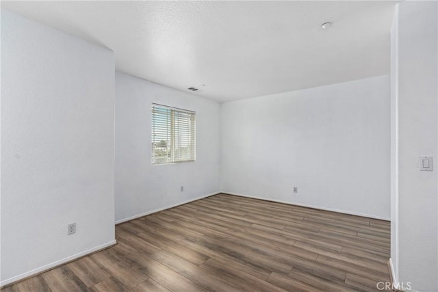 unfurnished room with wood finished floors and baseboards