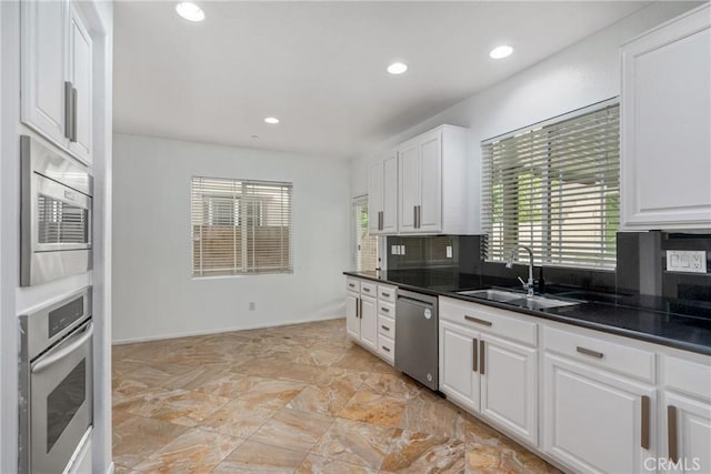 kitchen with stainless steel appliances, a sink, plenty of natural light, dark countertops, and recessed lighting