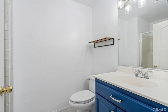 bathroom featuring toilet, vanity, a shower with shower door, and baseboards