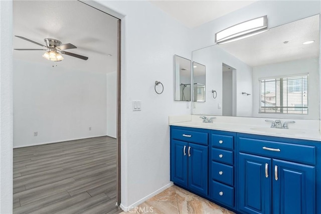 full bath with a ceiling fan, baseboards, double vanity, and wood finished floors