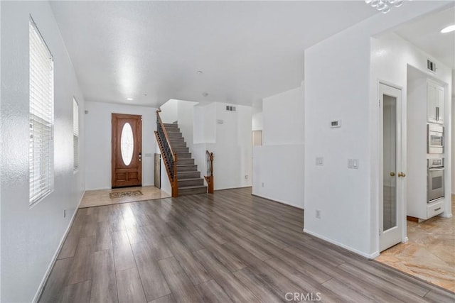 entryway featuring stairway, wood finished floors, and baseboards