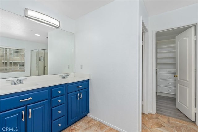 bathroom with a shower stall, double vanity, and baseboards