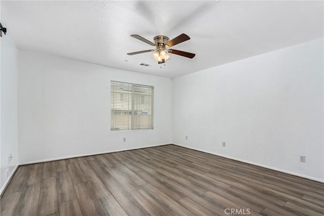 unfurnished room with dark wood finished floors, ceiling fan, and baseboards