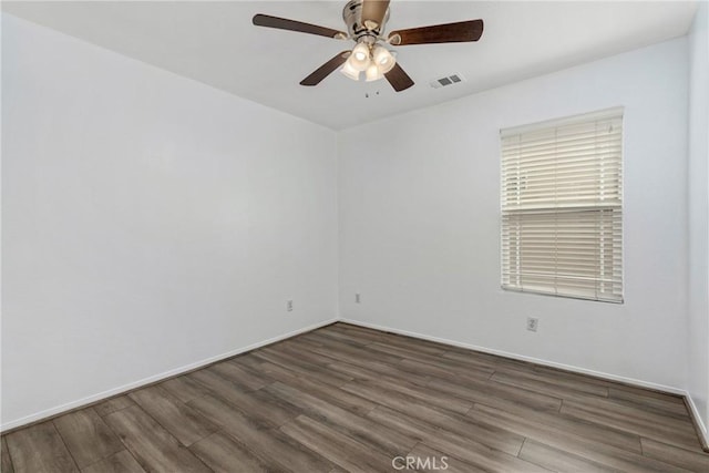 spare room with wood finished floors, a ceiling fan, and baseboards