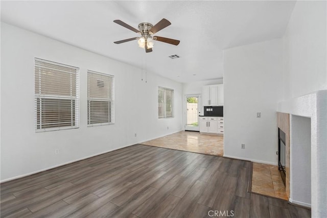 unfurnished living room featuring wood finished floors, a ceiling fan, and a fireplace