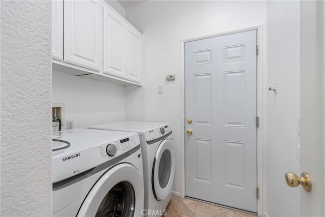 washroom featuring cabinet space, washing machine and clothes dryer, and light tile patterned flooring