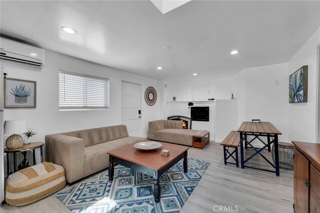 living area featuring a wall mounted air conditioner, light wood finished floors, and recessed lighting