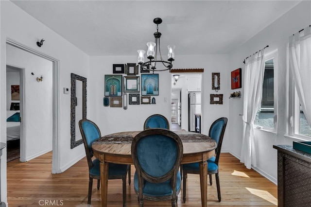 dining room featuring a chandelier, wood finished floors, and baseboards