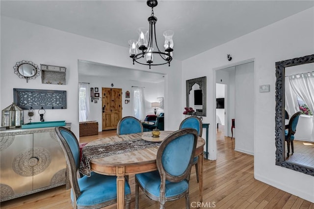 dining space featuring a chandelier, light wood-style floors, and baseboards