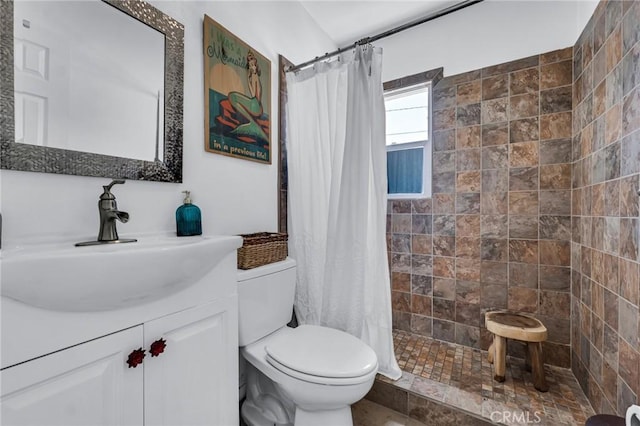 full bathroom featuring toilet, a tile shower, and vanity