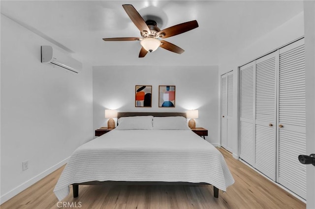 bedroom featuring an AC wall unit, light wood finished floors, baseboards, and a ceiling fan
