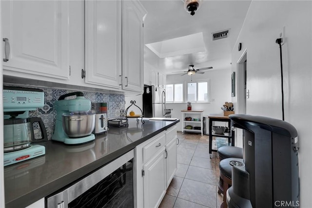 kitchen featuring wine cooler, freestanding refrigerator, a ceiling fan, and white cabinets