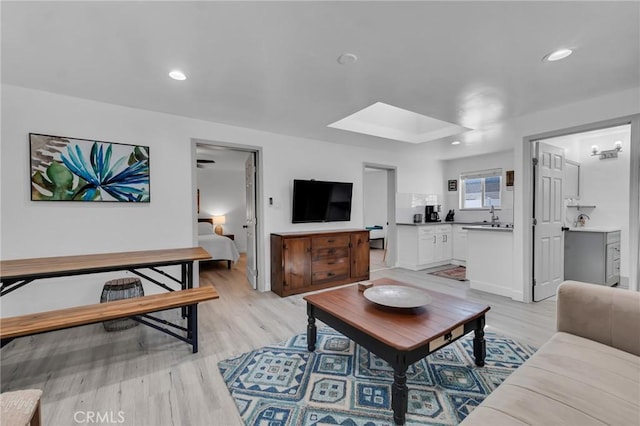 living room with light wood-style floors, recessed lighting, and a skylight
