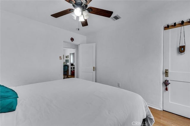 bedroom with wood finished floors, a barn door, and ceiling fan