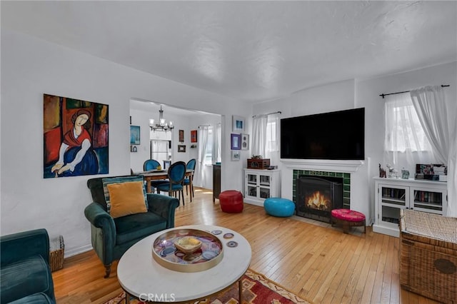 living room with a chandelier, hardwood / wood-style floors, and a tile fireplace