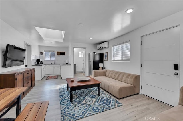 living room with a wall mounted AC, a skylight, light wood-style flooring, and recessed lighting