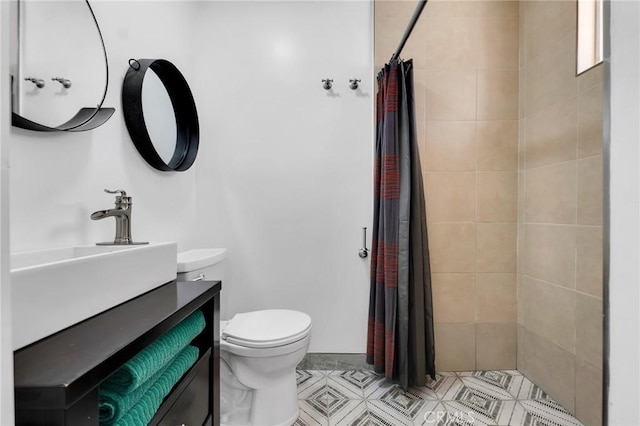 full bathroom with toilet, tiled shower, and vanity