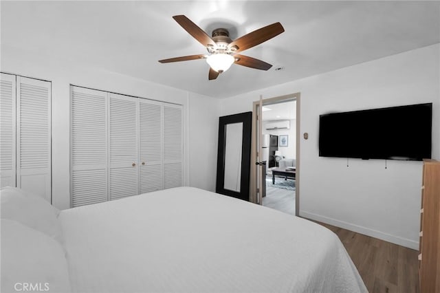 bedroom with wood finished floors, baseboards, a wall mounted AC, and ceiling fan