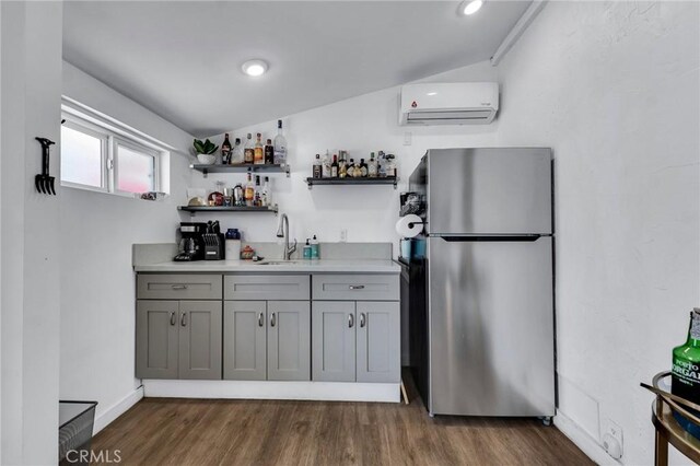 kitchen featuring freestanding refrigerator, a wall mounted AC, a sink, gray cabinetry, and dark wood-style flooring