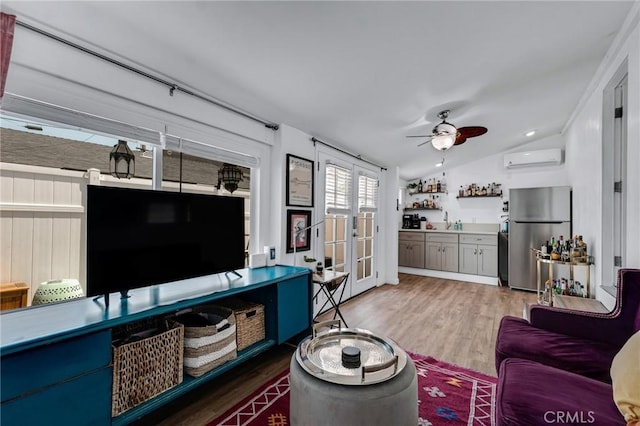 living room featuring a wall unit AC, wood finished floors, lofted ceiling, ceiling fan, and french doors