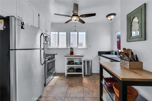 kitchen with appliances with stainless steel finishes, butcher block counters, plenty of natural light, and white cabinetry
