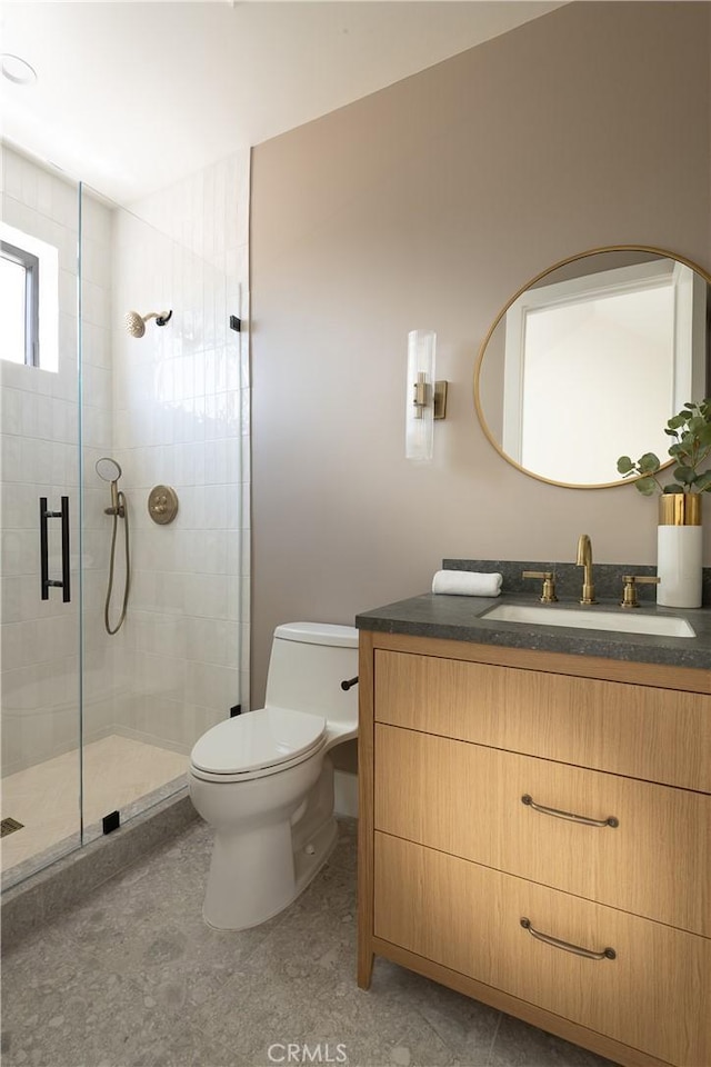 bathroom featuring a shower stall, toilet, and vanity
