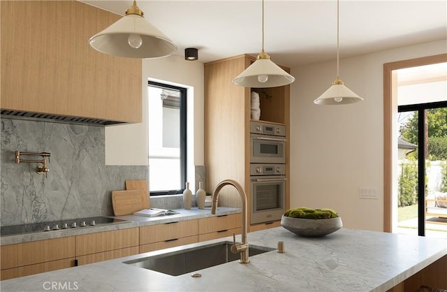 kitchen with a sink, modern cabinets, black electric stovetop, light brown cabinets, and decorative backsplash
