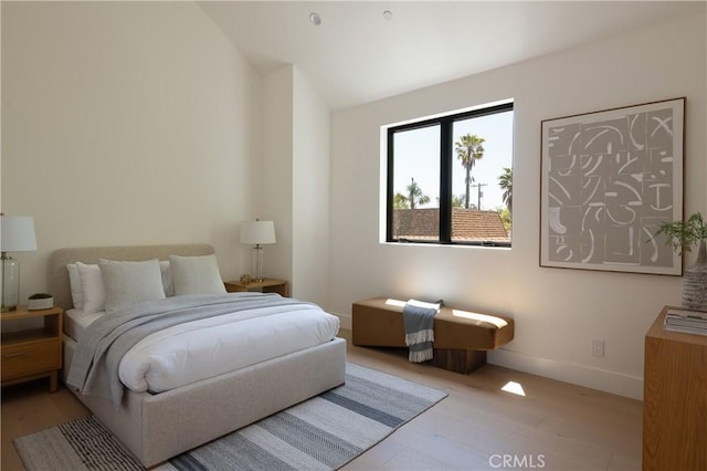 bedroom featuring wood finished floors, baseboards, and lofted ceiling