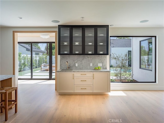 indoor wet bar with backsplash and light wood-type flooring