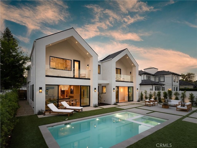back of property with a balcony, an outdoor living space, stucco siding, and a patio area