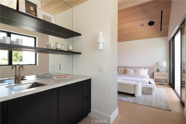 bedroom featuring a sink, wooden ceiling, light wood-type flooring, and baseboards