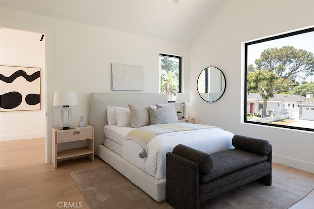 bedroom featuring light wood-type flooring, vaulted ceiling, and baseboards