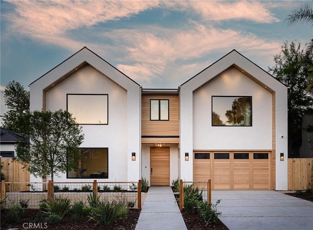 view of front of home featuring fence, concrete driveway, a garage, and stucco siding