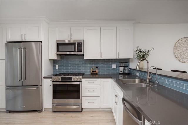 kitchen with appliances with stainless steel finishes, a sink, dark countertops, and decorative backsplash
